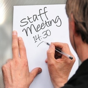 person writing staff meeting note